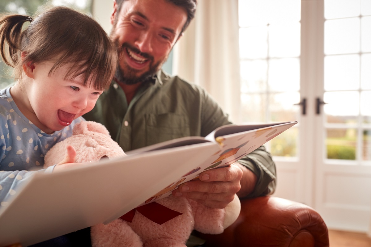 Little girl with Down's syndrome reading with her dad