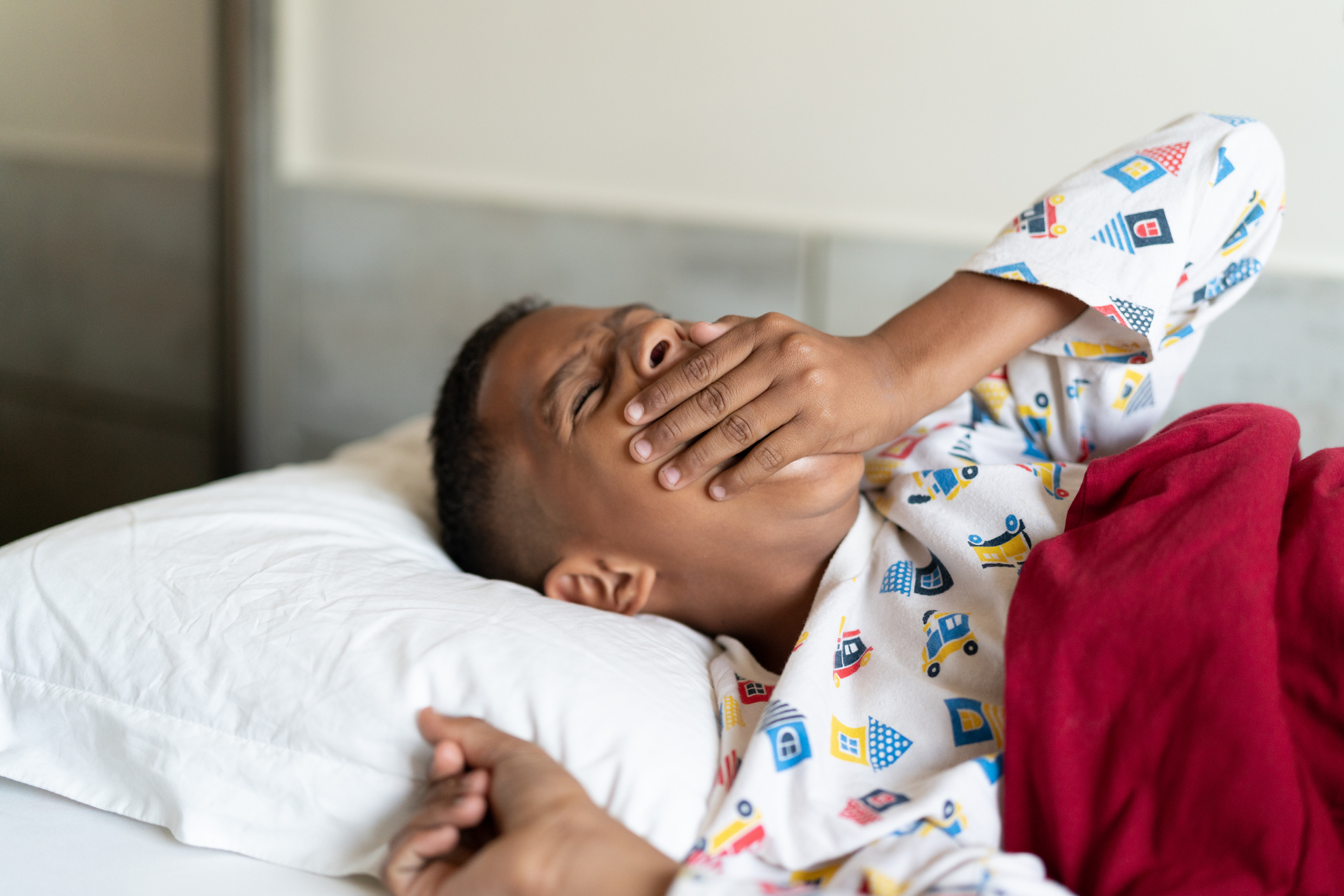 Teen boy in bed, yawning