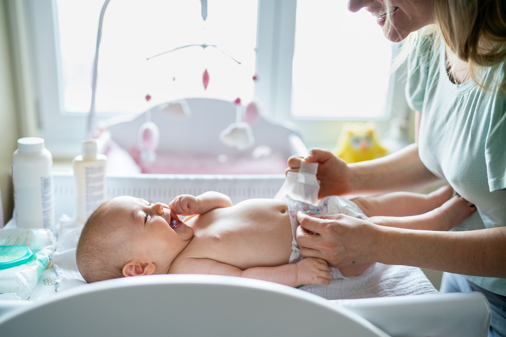 Smiling mum changing baby's nappy