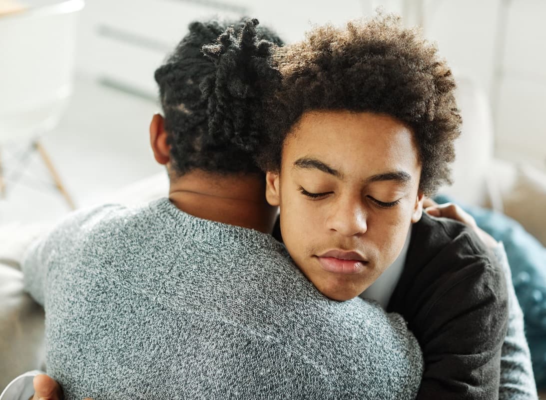 Teen boy being hugged by his dad