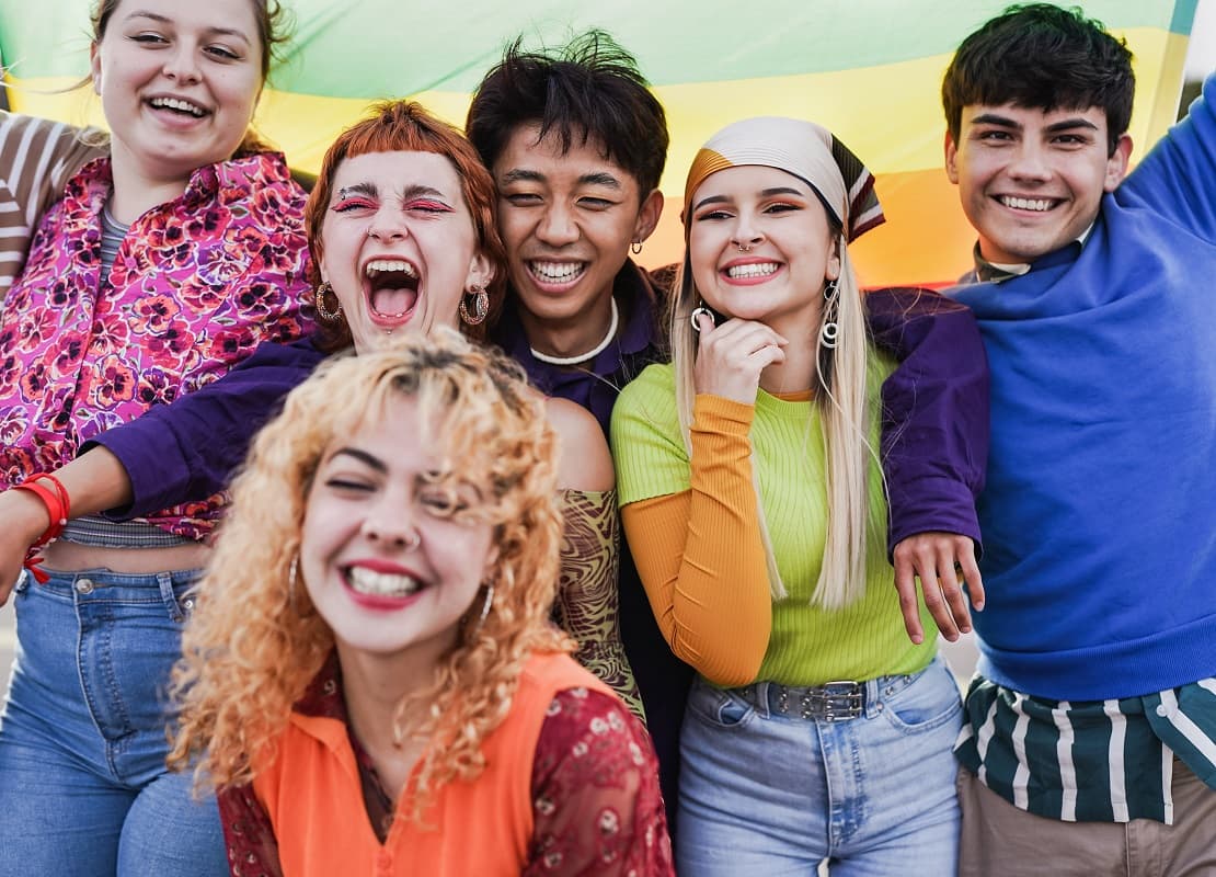 Happy teens standing in front of a rainbow banner