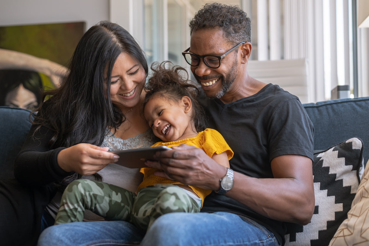 Mum and dad with young child looking at a mobile phone together