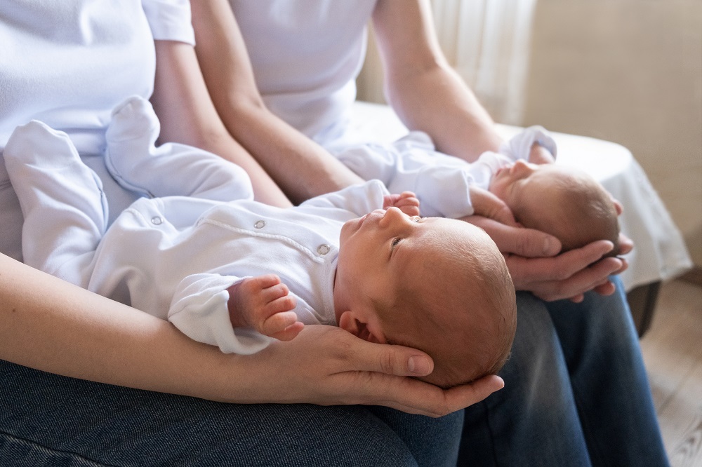 Parents holding twin new born babies on their laps
