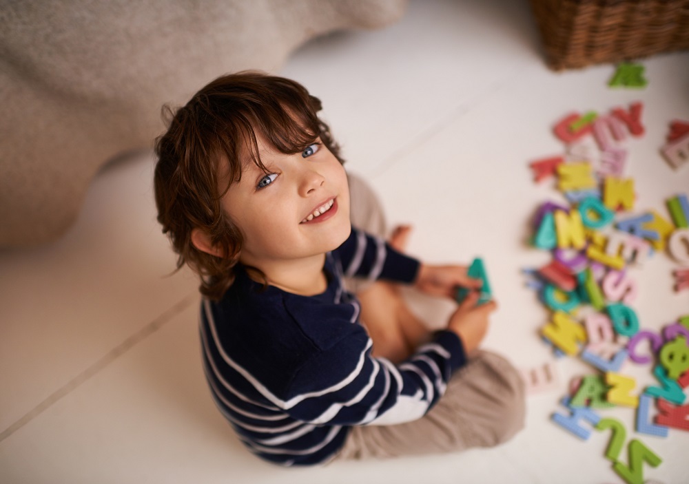Young boy playing a spelling game with colourful cut-out letters