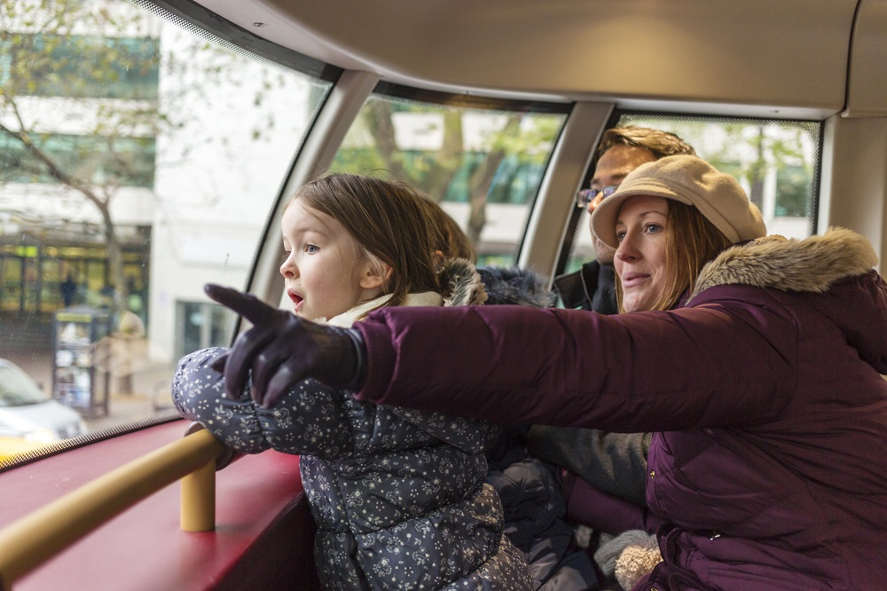 Mum and dad with young daughter looking out of a bus window