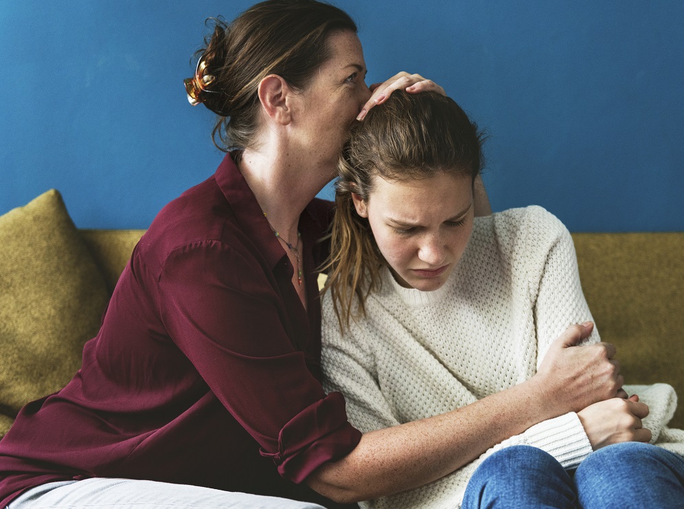 Concerned mum comforting her teenage daughter