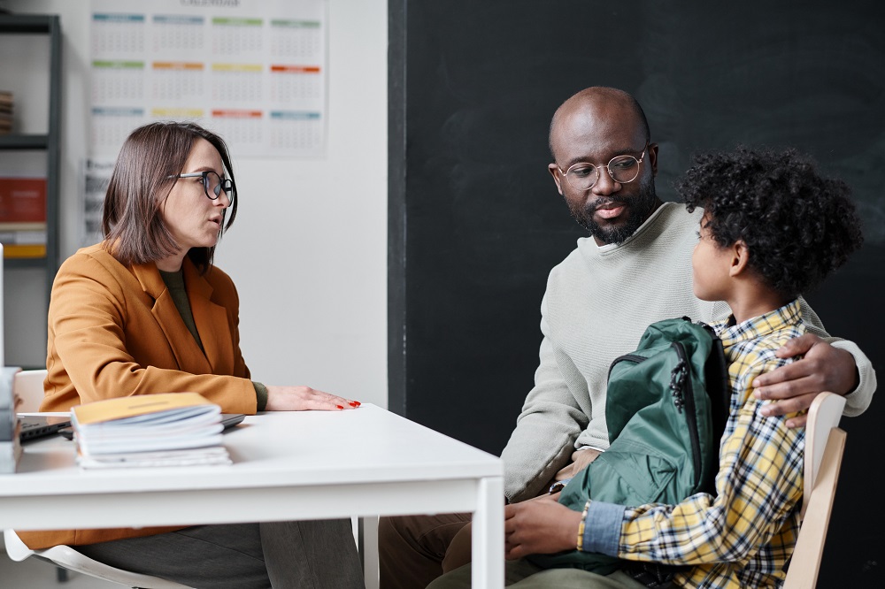 Dad and older boy talking to a teacher at school