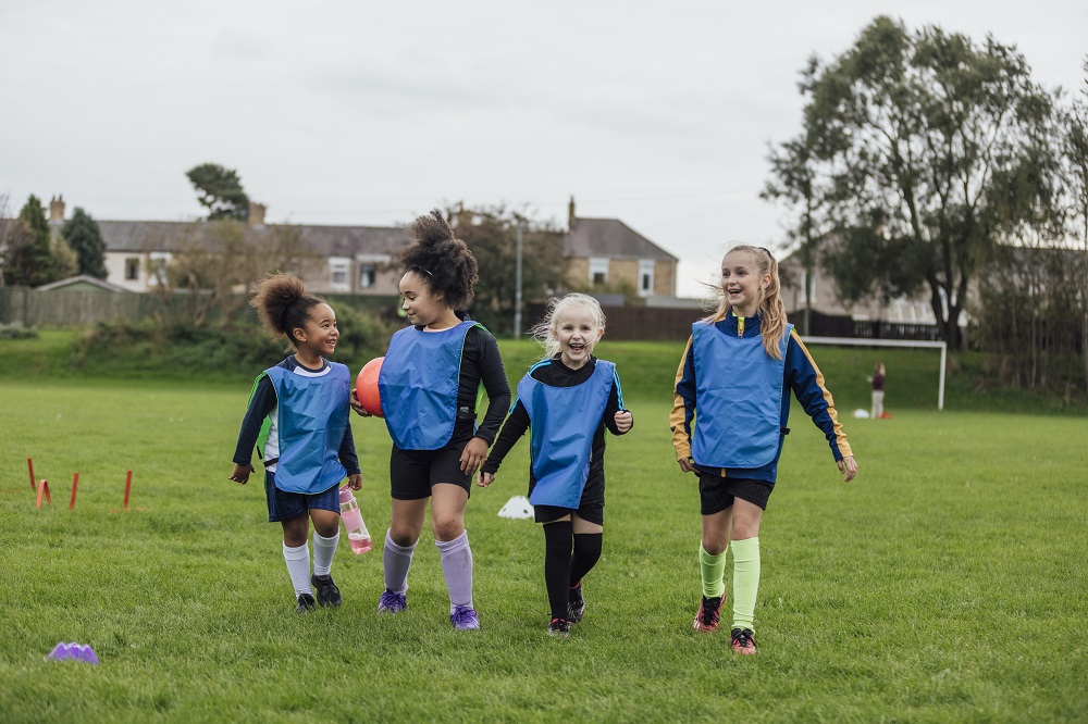 Young girls playing football in a park