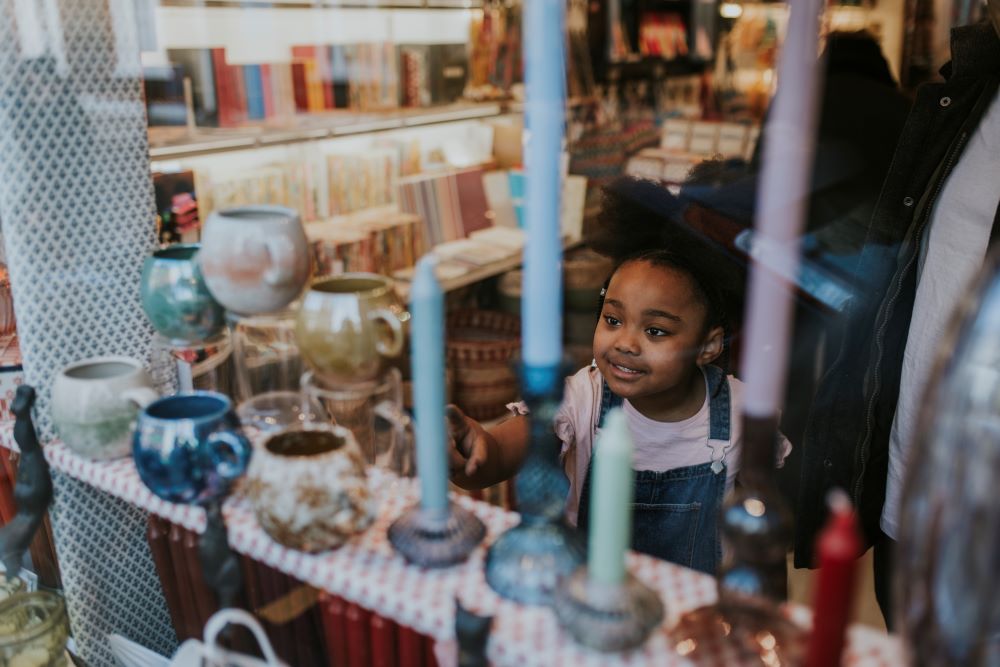 Young girl in a charity shop looking at objects for sale.
