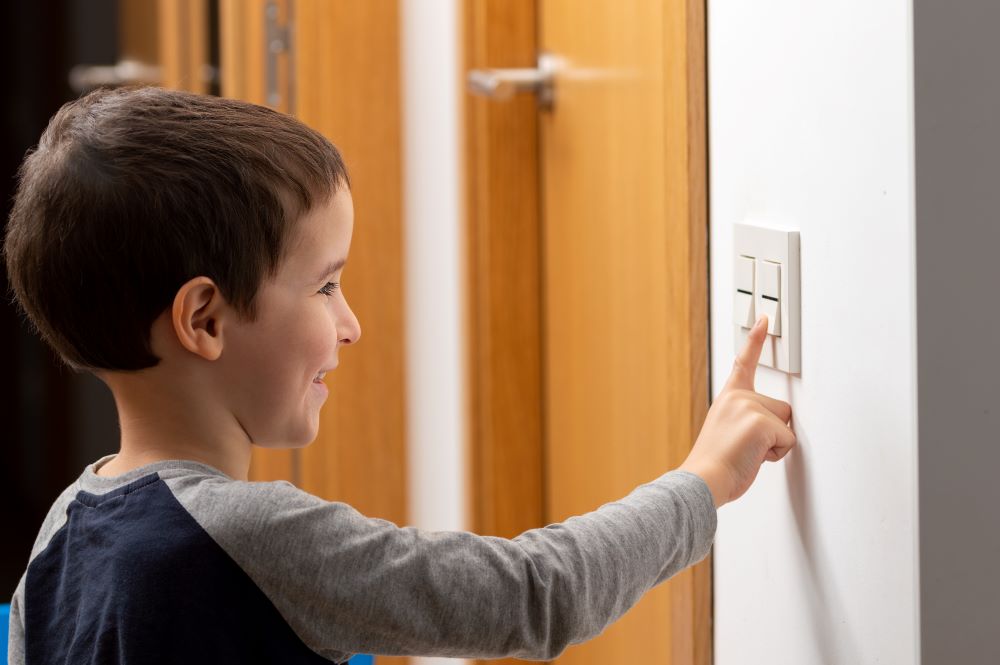 Young boy turning off a light switch.