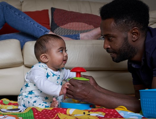 Dad playing with baby on a play mat.