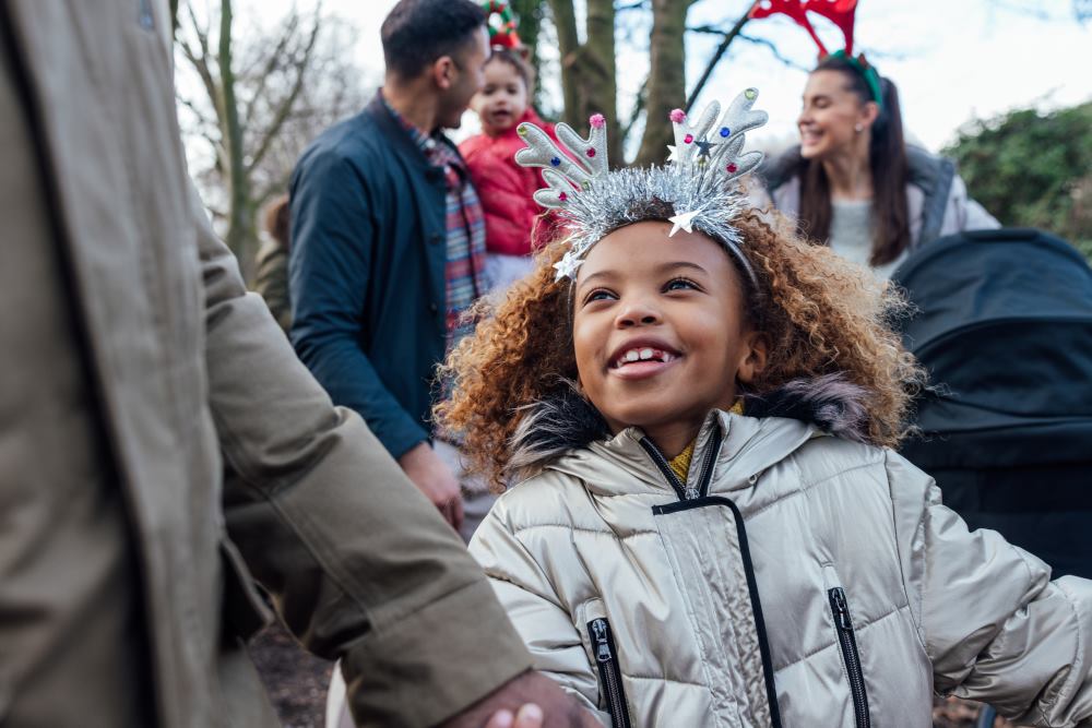 Young girl wearing festive antlers, going for a walk with her parent.