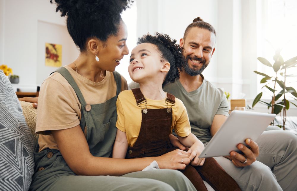Mum and dad talking to their child while looking at a tablet.
