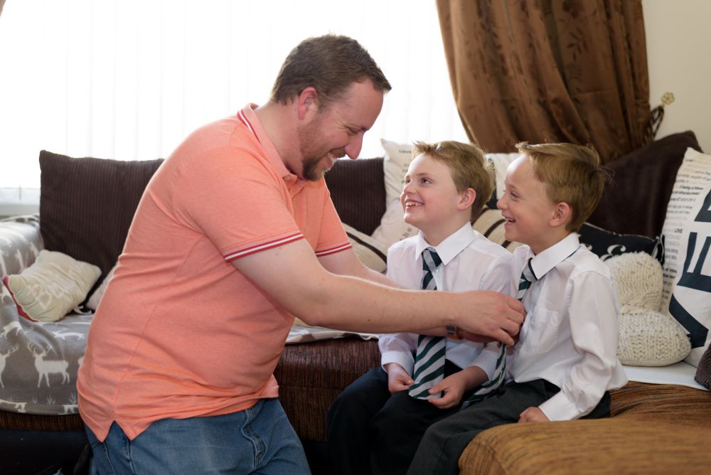 Dad helping his twin boys put their ties on ready for school.