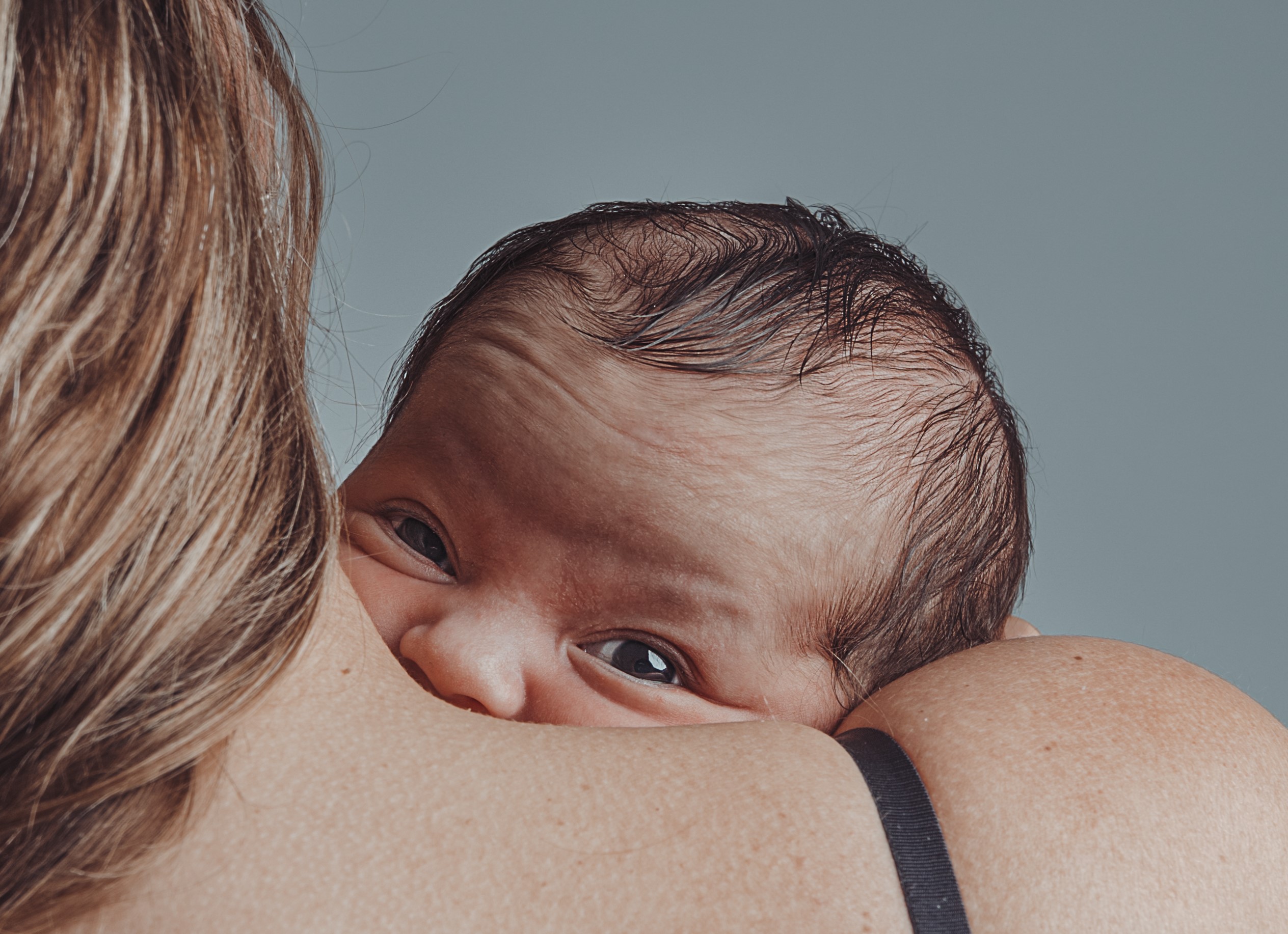 Cute baby looking over its mother's shoulder.