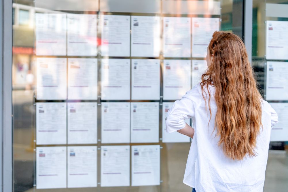 Woman looking at job adverts in a window.