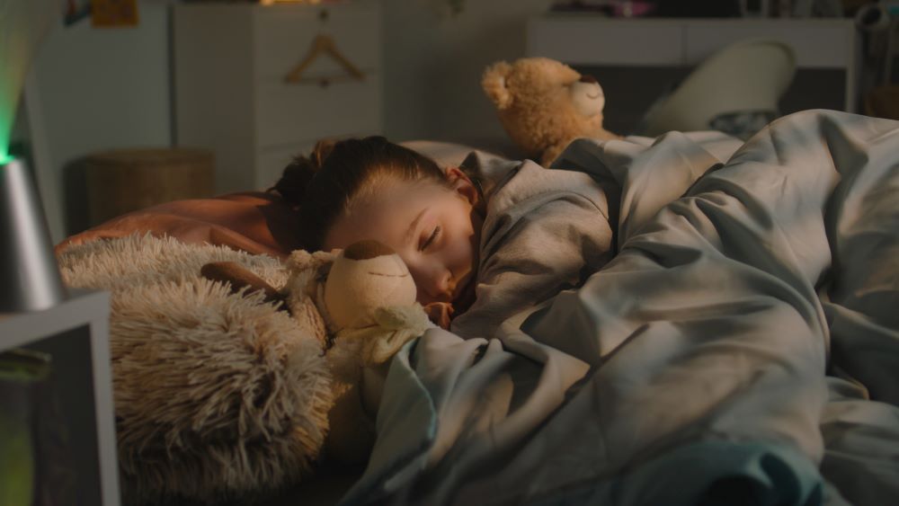 Young boy asleep in bed with toys.