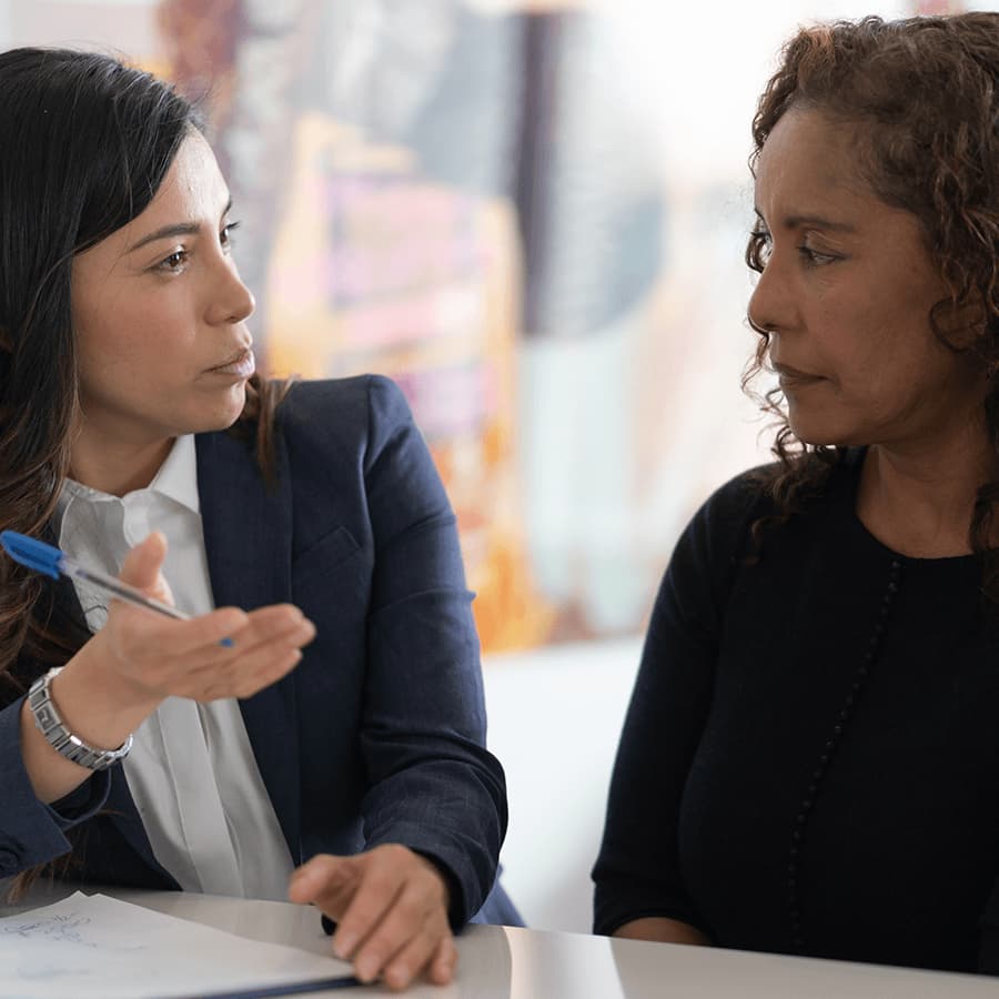 Woman talking together, one has forms and a pen