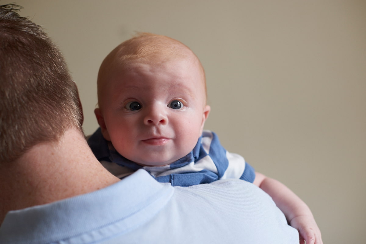 Photo of a dad holding a baby who is holding their head up 