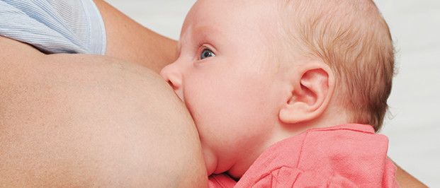 Photo of a baby suckling on its mother's nipple