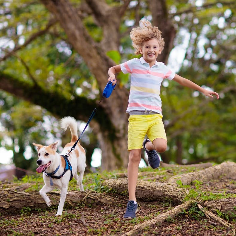 Boy and dog running together outdoors