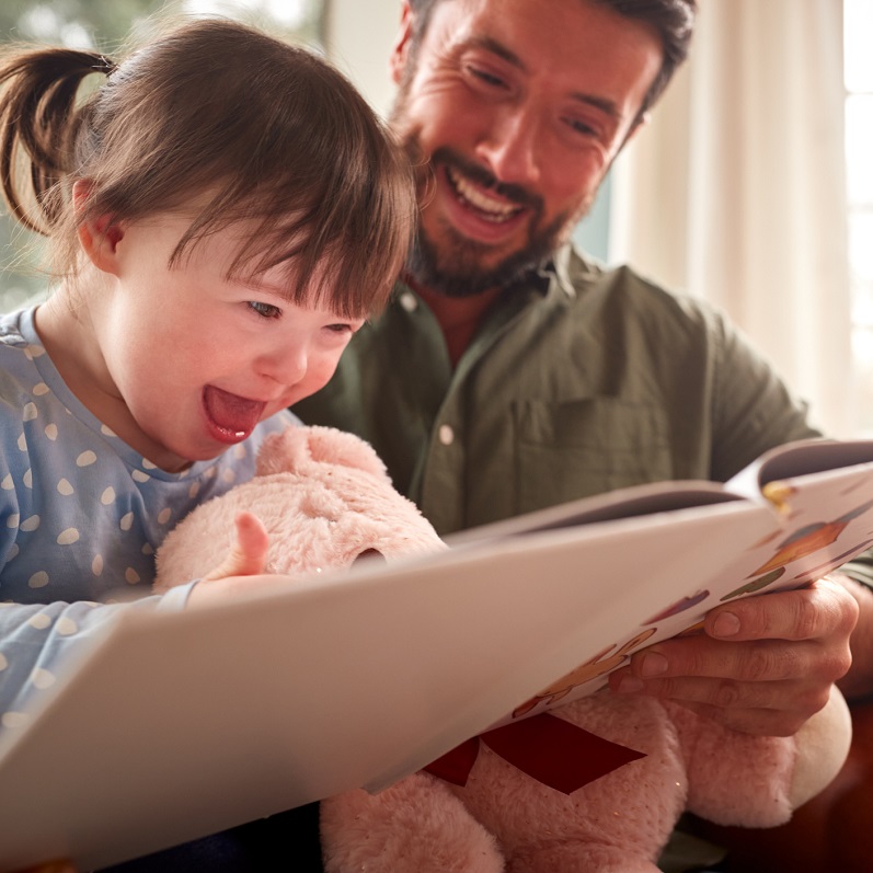 Child with Downs syndrome reading with her dad