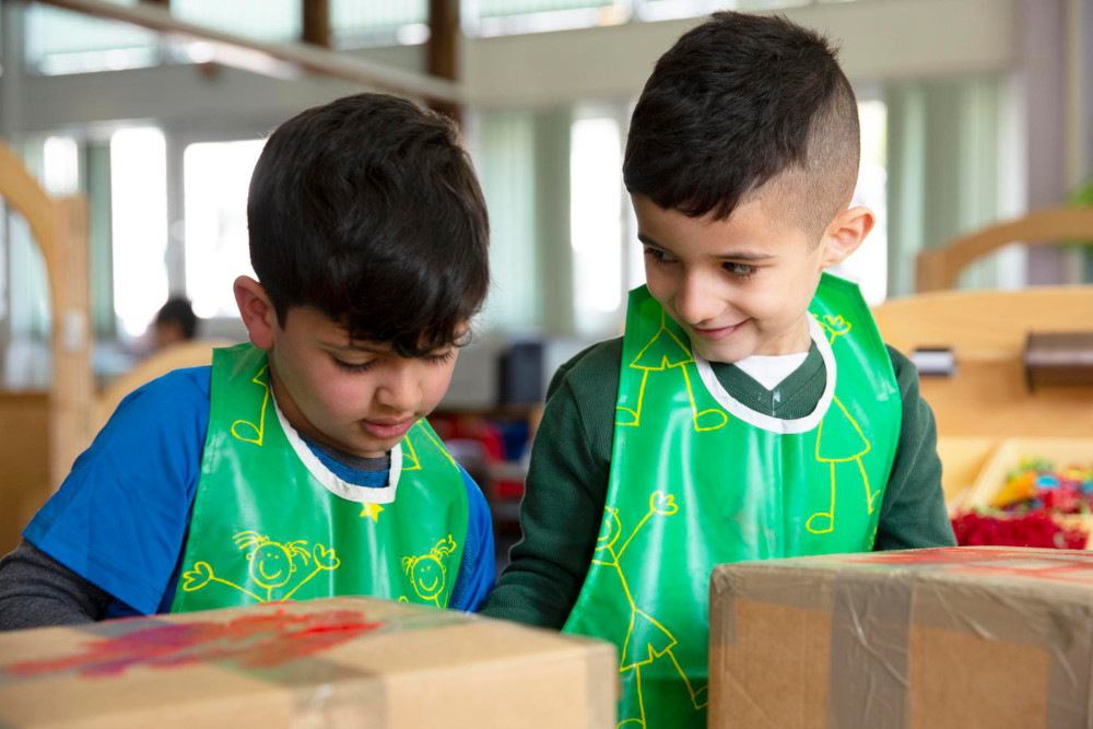 Image of two children wearing aprons in a playroom.