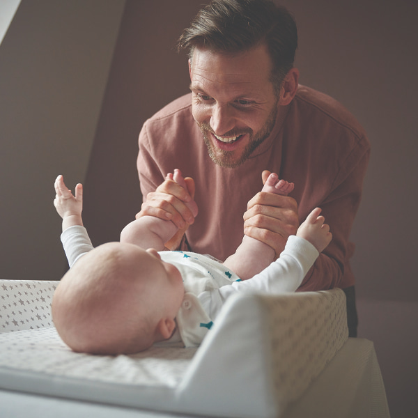 Photo of a dad smiling down at his baby on the chasing mat 