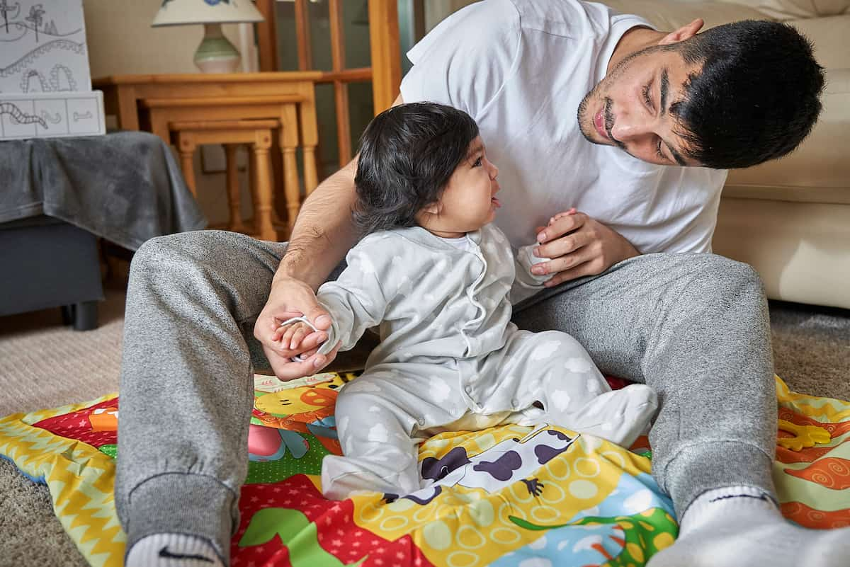 Photo of a baby sitting up supported by dad 