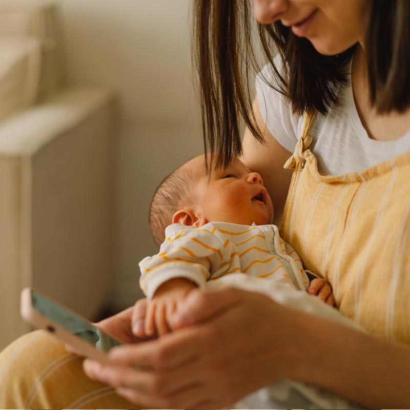 Mum holding sleeping baby making a phone call on her mobile
