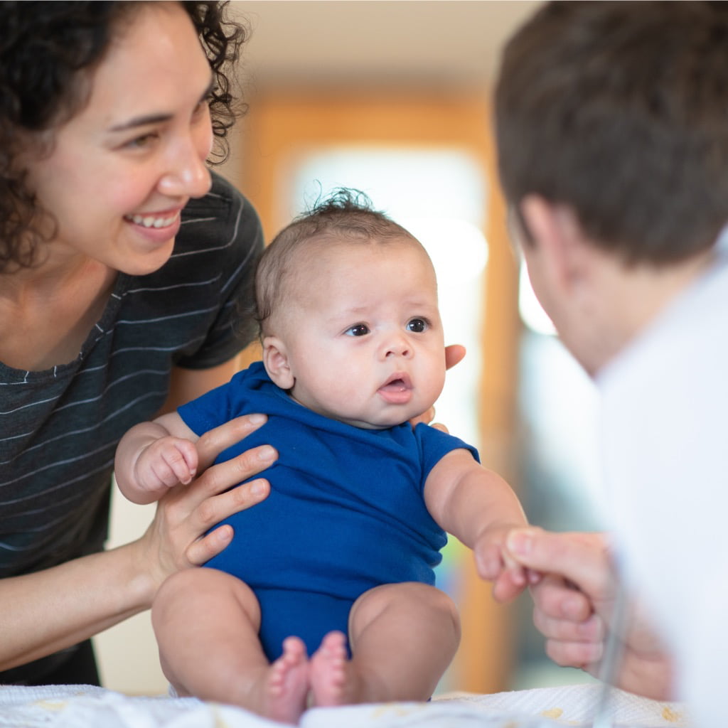 Photo of mum holding baby with other adult 