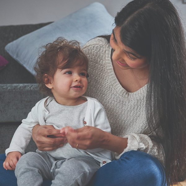 Photo of a mum cuddling her toddler on the couch 