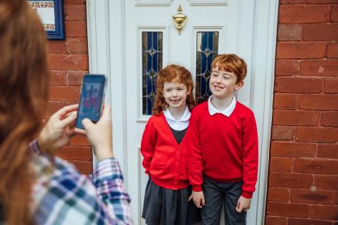 Children going back to school having their photo taken by mum