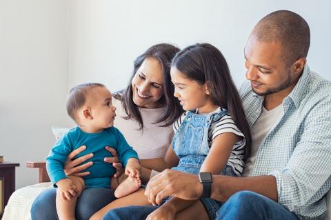 Mum and dad sitting on sofa with toddler and young girl