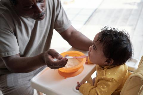 Dad feeding toddler in a highchair