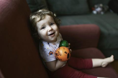 Smiling toddler playing with plastic balls at home