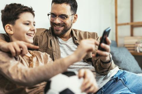 Dad and older boy looking at a mobile phone together and chatting