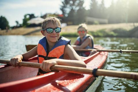 Young boys wearing life preservers in a kayak on a loch