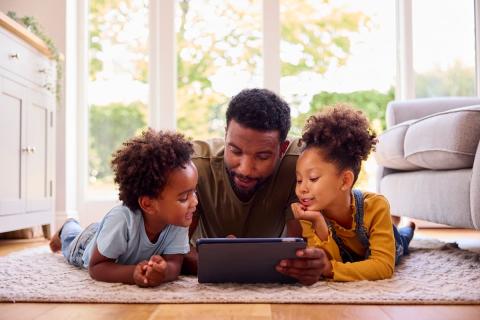 Father and two young children looking at a laptop