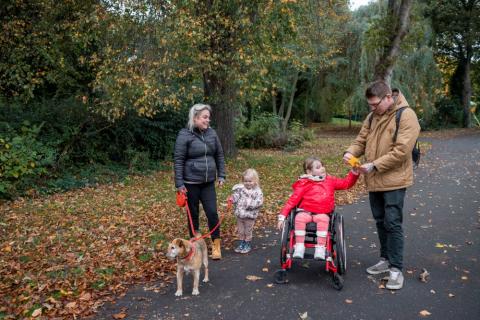 Mum dad and two children, one in a wheelchair, out for a walk with their dog on an autumn day