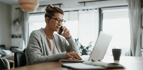 Woman on the phone, looking at a laptop