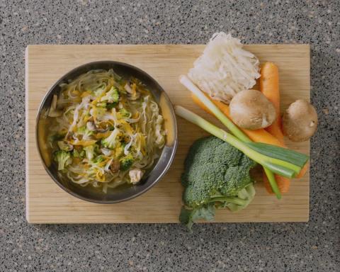 Bowl of chicken noodle soup with ingredients