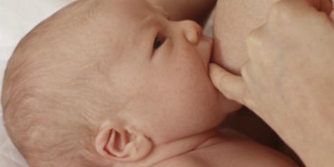 Photo of a mum breaking the suction of a baby who is breastfeeding 