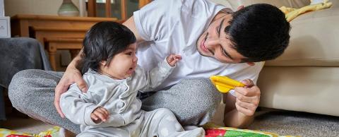 Baby and dad playing with toys on a play mat