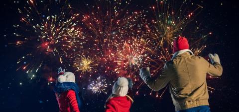 Children and parent in coats and woolly hats watching firework display