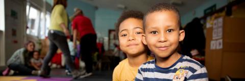 Image of two boys sitting on the floor and smiling at the camera.