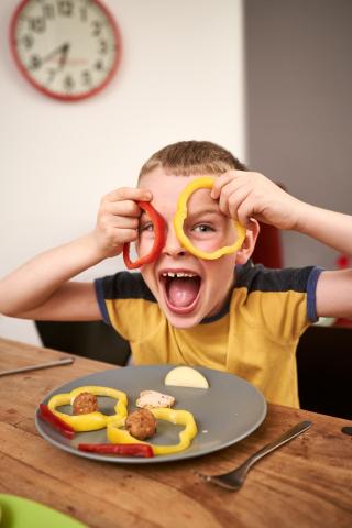 Photo of child holding peppers up to his face