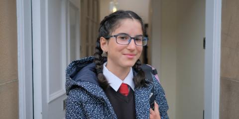 Photo of a girl standing in her school uniform in the doorway 