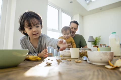 Child and toddler having breakfast with their dad