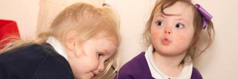 Image of two children sitting together in a nursery.